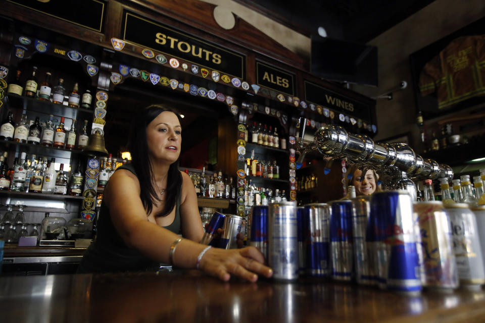 FILE - In this March 17, 2020, file photo bartender Courtney Schrag places beverage cans on the bar as she other employees prepare to close de Vere's Irish Pub in Sacramento, Calif. Local officials and businesses in the 13-county Greater Sacramento region were caught off guard last week when outdoor dining and worship services were OK again, hair and nail salons and other businesses could reopen, and retailers could allow more shoppers inside. It's still a mystery how the state made the decision or how and when it will lift the most serious restrictions on the bulk of the state's population because officials won't share their data. (AP Photo/Rich Pedroncelli, File)