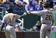 Oakland Athletics' Josh Harrison (1) and Mark Canha (20) celebrate after scoring on a single by Chad Pinder during the third inning of a baseball game against the Kansas City Royals Thursday, Sept. 16, 2021, in Kansas City, Mo. (AP Photo/Charlie Riedel)