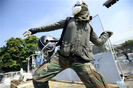 An anti-government protester throws a rock at Thai riot police as they attempt to remove barricades outside Government House in Bangkok December 2, 2013. REUTERS/Dylan Martinez