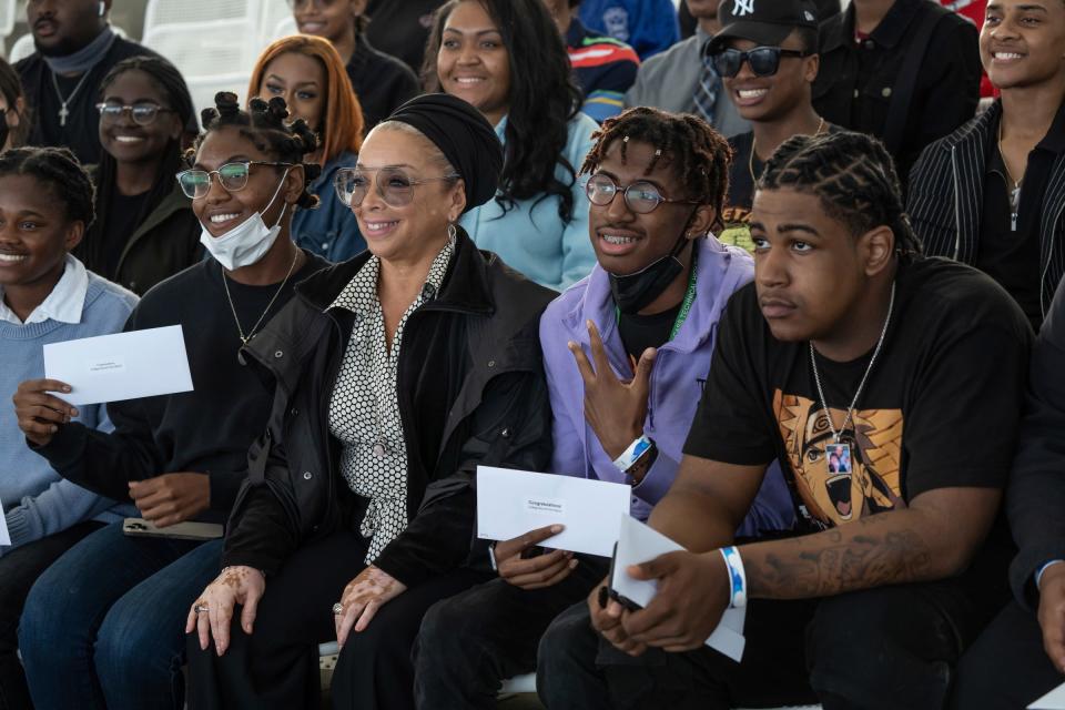 The Right Productions president Shahida Mausi, center, sits with a group of metro Detroit high school graduates selected to receive a $500 scholarship for a photo during the annual Young Gifted and College Bound communitywide graduation and college send-off ceremony at the Aretha Franklin Amphitheatre in Detroit on May 25, 2022.