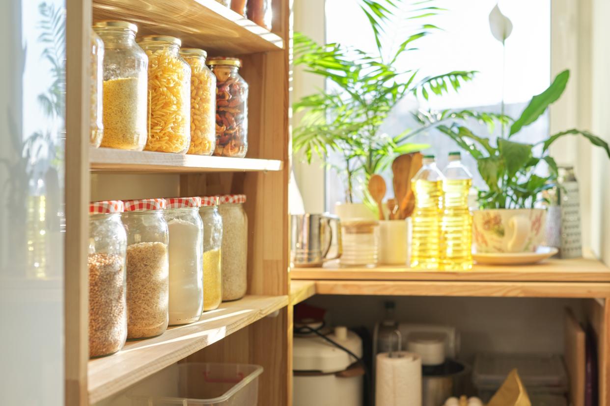 Food storage at home, sunflower oil on table in pantry. Pantry interior, wooden shelf with food cans and kitchen utensils