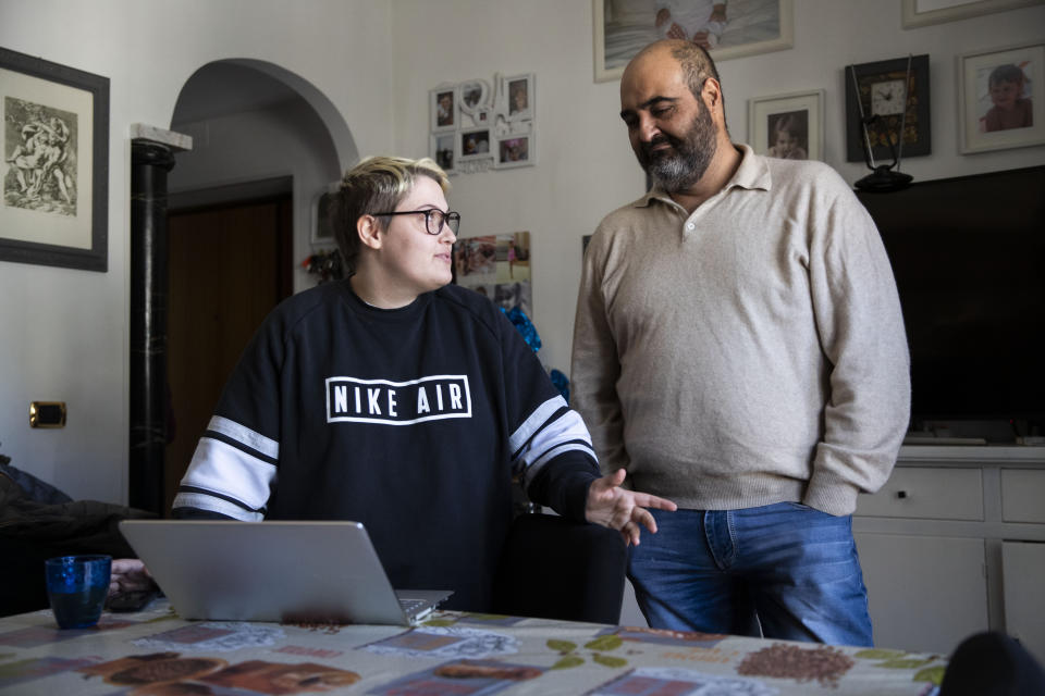 Matteo talks with his father Franco Coccimiglio in their kitchen in Rome, Saturday, March 20, 2021. Matteo is an 18-year-old student who identifies as a man and is in the process of changing his legal gender from female to male. The Ripetta school of art in Rome - where he studies - recently joined a handful of high schools in Italy that give transgender students the right to be known by a name other than the one they were given at birth. The initiative is meant to create an environment where transgender students feel secure and reflects a growing awareness in Italy of gender dysphoria among teenagers and children. (AP Photo/Alessandra Tarantino)