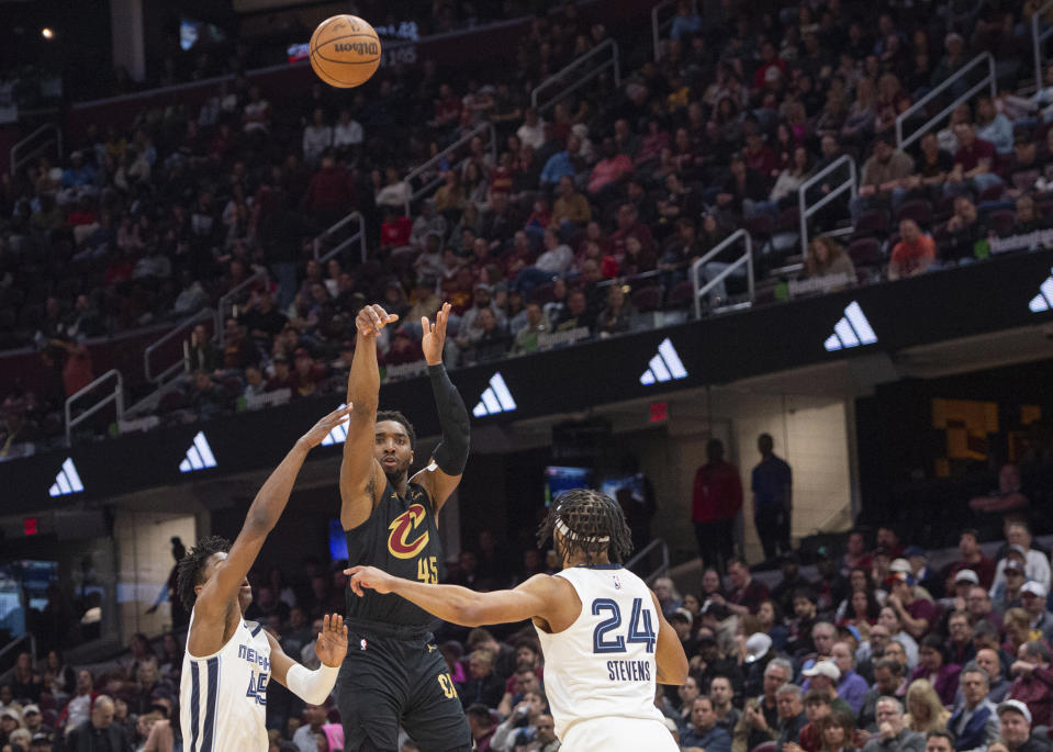 Cleveland Cavaliers' Donovan Mitchell (45) shoots between Memphis Grizzlies' GG Jackson (45), left, and Lamar Stevens (24) during the first half of an NBA basketball game in Cleveland, Wednesday, April 10, 2024. (AP Photo/Phil Long)