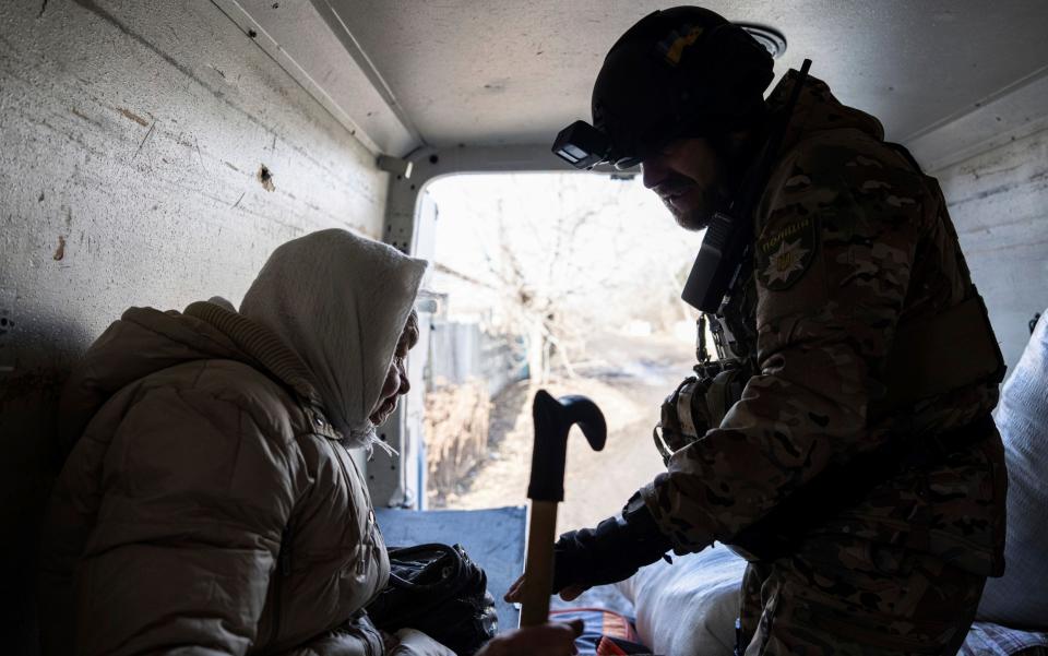 Police officer helps an elderly woman to evacuate Bakhmut - AP