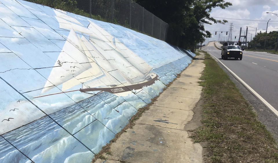 FILE - Traffic passes a mural of the slave ship Clotilda along Africatown Boulevard, in Mobile, Ala., May 30, 2019. Republican Tommy Tuberville told people Saturday, Oct. 8, 2022, at an election rally in Nevada that Democrats support reparations for the descendants of enslaved people because “they think the people that do the crime are owed that.” His remarks cut deeply for some, especially in and around Africatown, a community in Mobile, Alabama, that was founded by descendants of Africans smuggled in 1860 to the United States aboard a schooner called the Clotilda. (AP Photo/Kevin McGill, File)