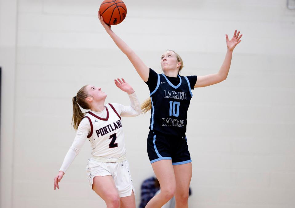 Lansing Catholic's Anna Richards, right, pulls down a rebound over Portland's Malia Thelen, Friday, March 8, 2024, at Portland High School.