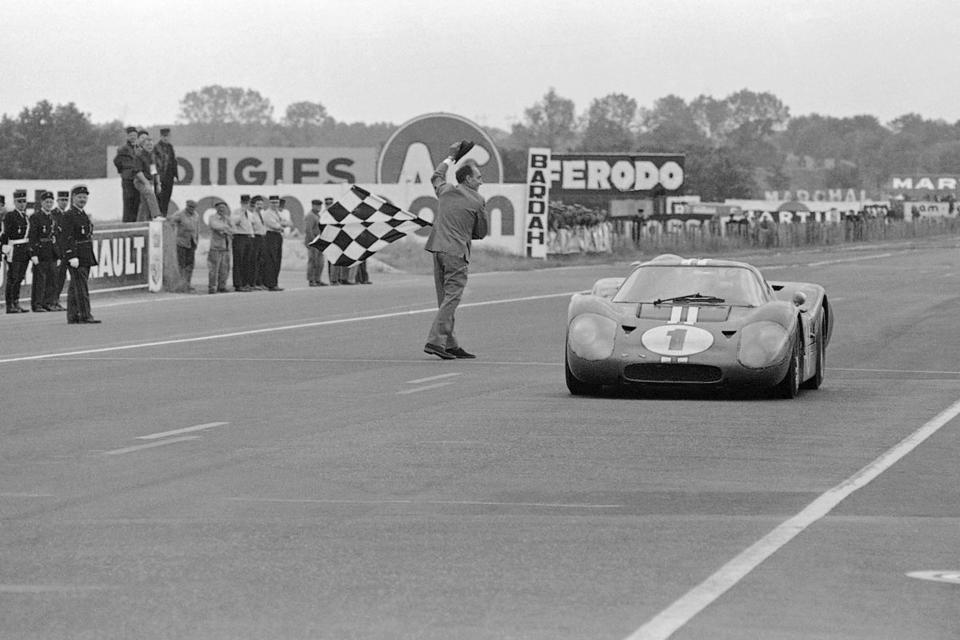 FILE - A.J. Foyt gets a checkered flag and a hats-off salute from race officials as he drives new Ford Mark IV across finish line at Le Mans, France, June 11, 1967 for victory in the 24 hour automobile race. (AP Photo/File)