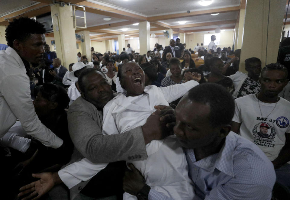 Marie Michelle Joachin, the mother of murdered community leader Josemano "Badou" Victorieux is restrained as she mourns during Victorieux's funeral in Port-au-Prince, Haiti, Wednesday, Oct. 16, 2019. Family members plan to bury three of the people killed in recent violence related to protests calling for the resignation of President Jovenel Moise. Haiti has entered into a fifth week of deadly protests that have paralyzed the economy and shuttered schools. (AP Photo/Rebecca Blackwell)