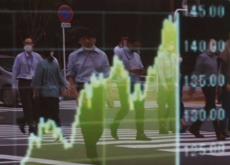 A man uses a mobile phone in front of a board displaying a graph of the Japanese yen exchange rate against the U.S. dollar outside a brokerage in Tokyo