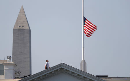 A worker looks up after lowering the flag over the White House in Washington to half-staff to honor victims of the shooting at the Capital Gazette Newspaper in Annapolis, Maryland, U.S., July 3, 2018. REUTERS/Kevin Lamarque