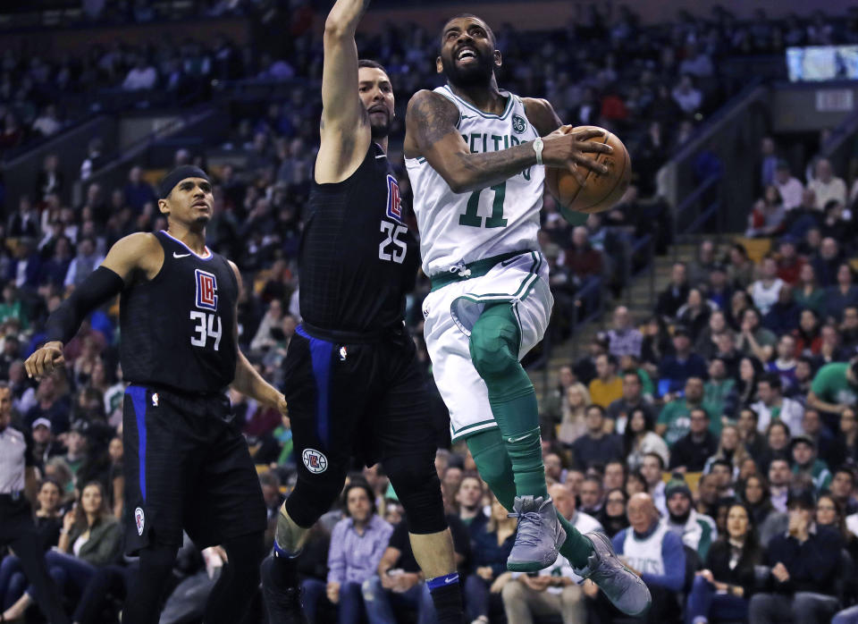 Boston Celtics guard Kyrie Irving (11) drives past Los Angeles Clippers guard Austin Rivers (25) and forward Tobias Harris (34) during the first quarter of an NBA basketball game in Boston, Wednesday, Feb. 14, 2018. (AP Photo/Charles Krupa)