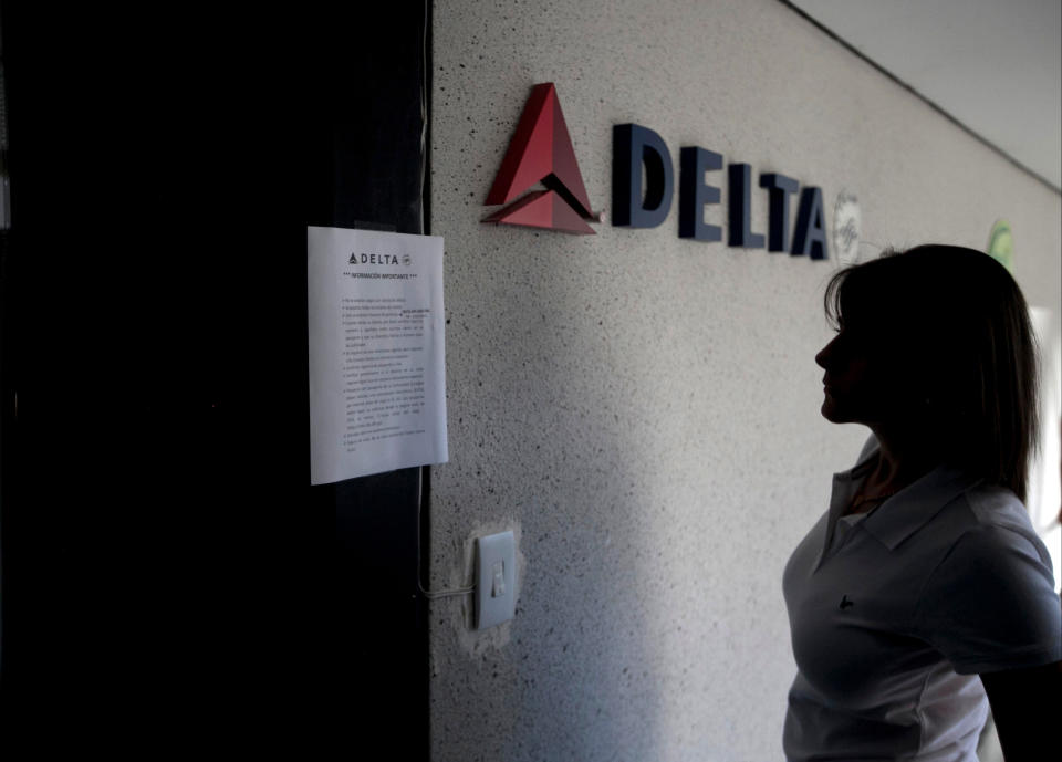 Una mujer lee un aviso en la puerta cerrada de la agencia de Delta Airlines en Caracas, Venezuela, viernes 24 de enero de 2014. United, Delta, American Airlines, la panameña Copa Airlines y otras aerolíneas cerraron sus oficinas o dejaron de vender pasajes después que el gobierno devaluó el bolívar para los vuelos al exterior. (AP Foto/Alejandro Cegarra)