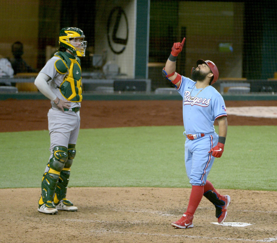 Texas Rangers' Rougned Odor celebrates as he touches home plate after hitting a three-run home run in the sixth inning of a baseball game against the Oakland Athletics in Arlington, Texas, Sunday, Sept. 13, 2020. Athletics catcher Jonah Heim, left, looks on. (AP Photo/Matt Strasen)