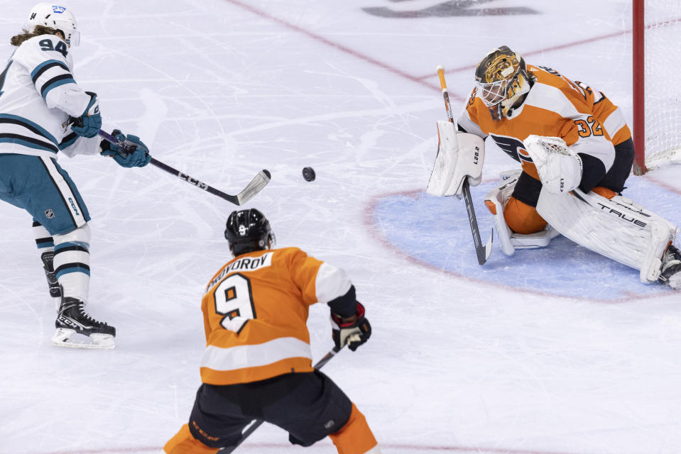 San Jose Sharks left wing Alexander Barabanov (94) attempts a shot on goal, deflected by Philadelphia Flyers goaltender Felix Sandstrom (32) as defenseman Ivan Provorov (9) follows during the first period of an NHL hockey game, Sunday, Oct. 23, 2022, in Philadelphia. (AP Photo/Laurence Kesterson)