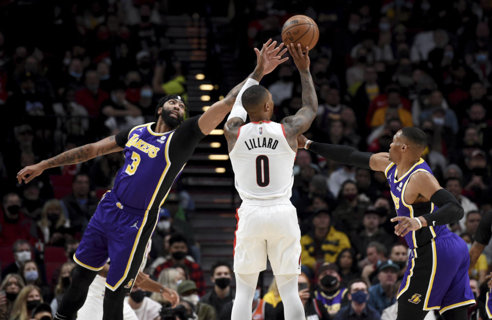 Portland Trail Blazers guard Damian Lillard, center, hits a 3-point shot from between Los Angeles Lakers Anthony Davis, left, and guard Russell Westbrook during the first half of an NBA basketball game in Portland, Ore., Saturday, Nov. 6, 2021. (AP Photo/Steve Dykes)