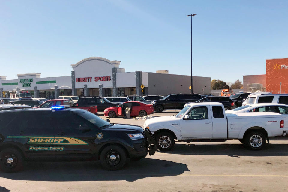Law enforcement work the scene where two men and a woman were fatally shot Monday, Nov. 18, 2019, outside a Walmart store in Duncan, Okla. Two victims were shot inside a car and the third was in the parking lot outside the store in Duncan, Police Chief Danny Ford said. (AP Photo/Sean Murphy)