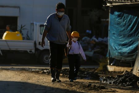 A man walks with his son near flooded houses, in the aftermath of Typhoon Hagibis, in Yanagawamachi district, Date City
