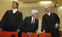 F1 CEO Bernie Ecclestone, center, stands with his lawyers Sven Thomas, right, and Norbert Scharf as he arrives in the court in Munich, southern Germany, Thursday, April 24, 2014. Ecclestone is charged with bribery and incitement to breach of trust "in an especially grave case" over a US$ 44 million payment to a German banker, that prosecutors allege was meant to facilitate the sale of the Formula One Group to a buyer of Ecclestone's liking. (AP Photo/Michaela Rehle, pool)