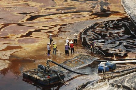 Labourers work to drain sewage water from a leaked sewage tank at a copper mine in Shanghang, Fujian province, in this July 13, 2010 file photo. REUTERS/Stringer