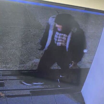 Surveillance image of a man wearing a black beanie, black shirt, black shorts, black pants and black shoes.