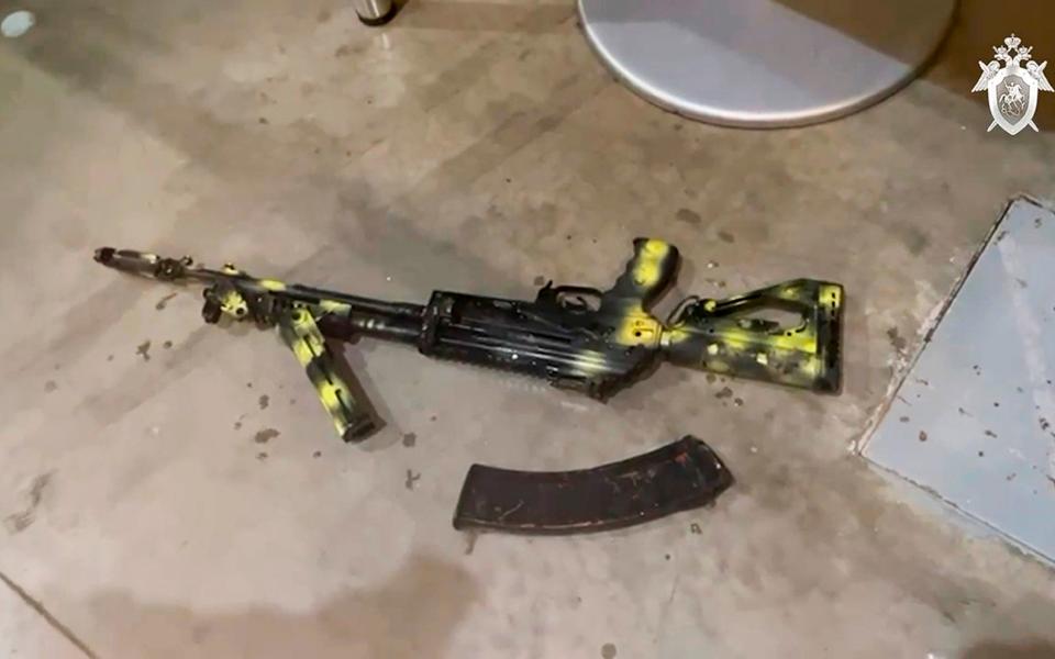 a Kalashnikov assault rifle lies on the ground as Investigators from the