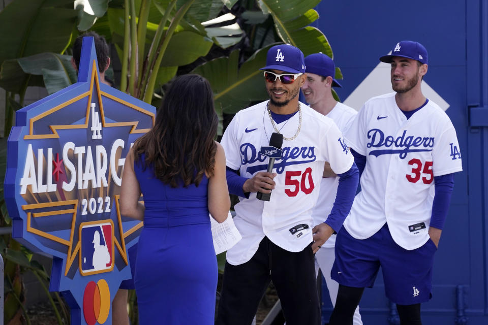 Los Angeles Dodgers' Mookie Betts, second from left, speaks with Alanna Rizzo, left, of the MLB Network as Walker Buehler, second from right, and Cody Bellinger look on during an event to officially launch the countdown to MLB All-Star Week Tuesday, May 3, 2022, at Dodger Stadium in Los Angeles. The All-Star Game is scheduled to be played on July 19. (AP Photo/Mark J. Terrill)