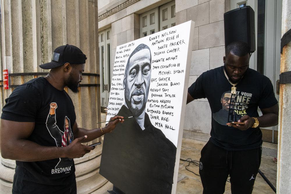 Artist Dennis Owes, 31, from Ghana gives the last touch to his portrait of George Floyd during a rally on Sunday, May 23, 2021, in Brooklyn borough of New York. (AP Photo/Eduardo Munoz Alvarez)