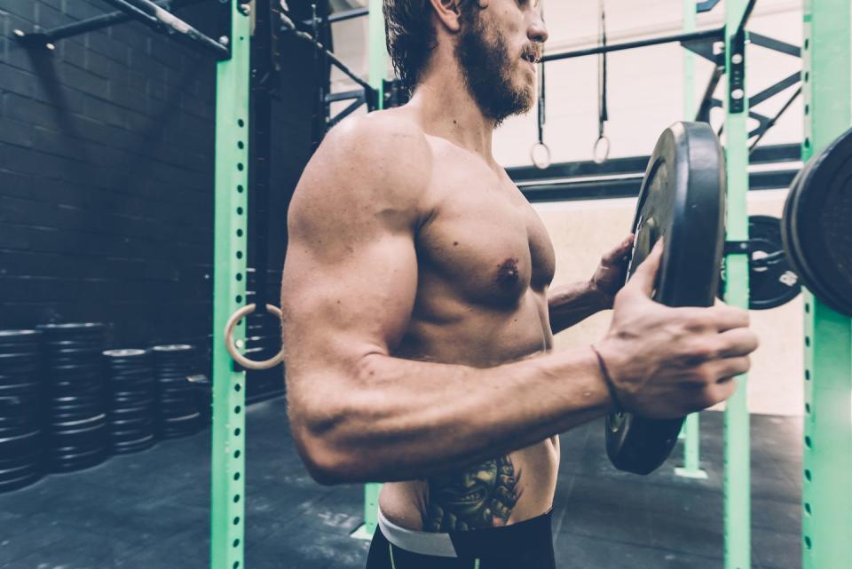 young male cross trainer preparing barbell in gym