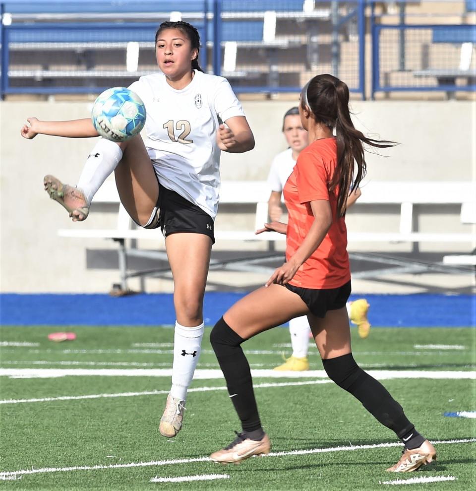 Abilene High's Amaris Amaya (12) leaps for the ball as an El Paso High player looks on.