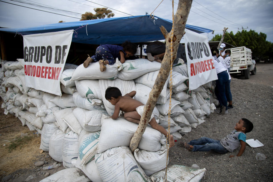 Children play on sandbags at a checkpoint set up by their mothers, who say they are part of a female-led, self-defense group, to protect the entrance of their town of El Terrero in Michoacan state, Mexico, Wednesday, Jan. 13, 2021. Many of the women vigilantes in the hamlet of El Terrero have lost sons, brothers or fathers in the fighting. (AP Photo/Armando Solis)