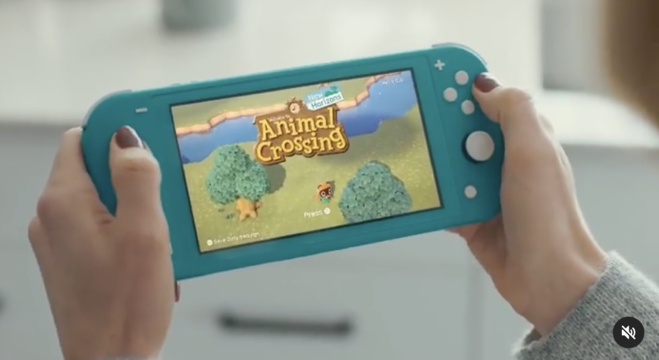 Person holding a game console with 'Animal Crossing' on the screen