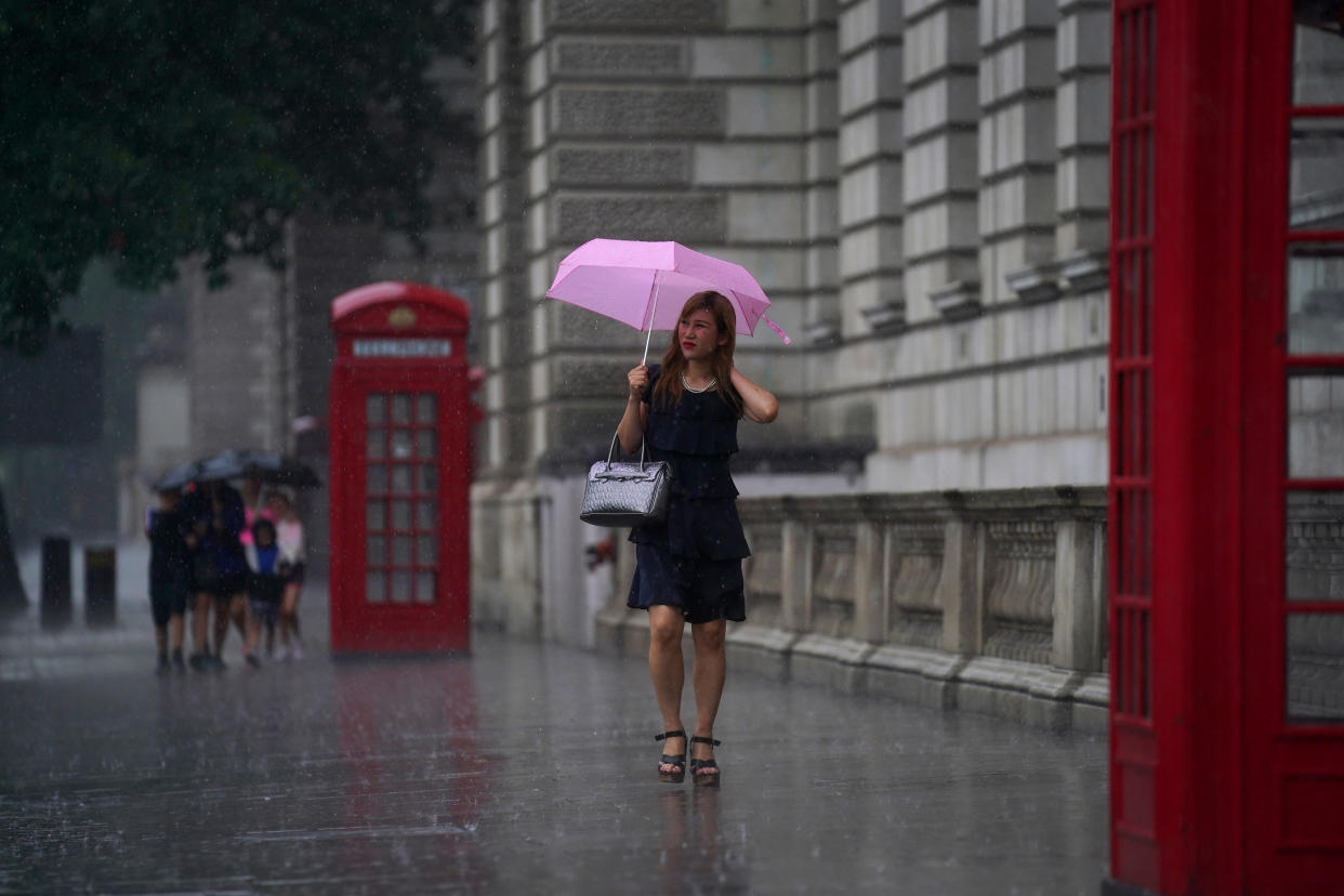 A woman walks through Parliament Square as heavy rain sweeps through central London. Thunderstorms bringing lightning and torrential rain to the south are set to continue until Monday, forecasters have said. Picture date: Sunday July 25, 2021.