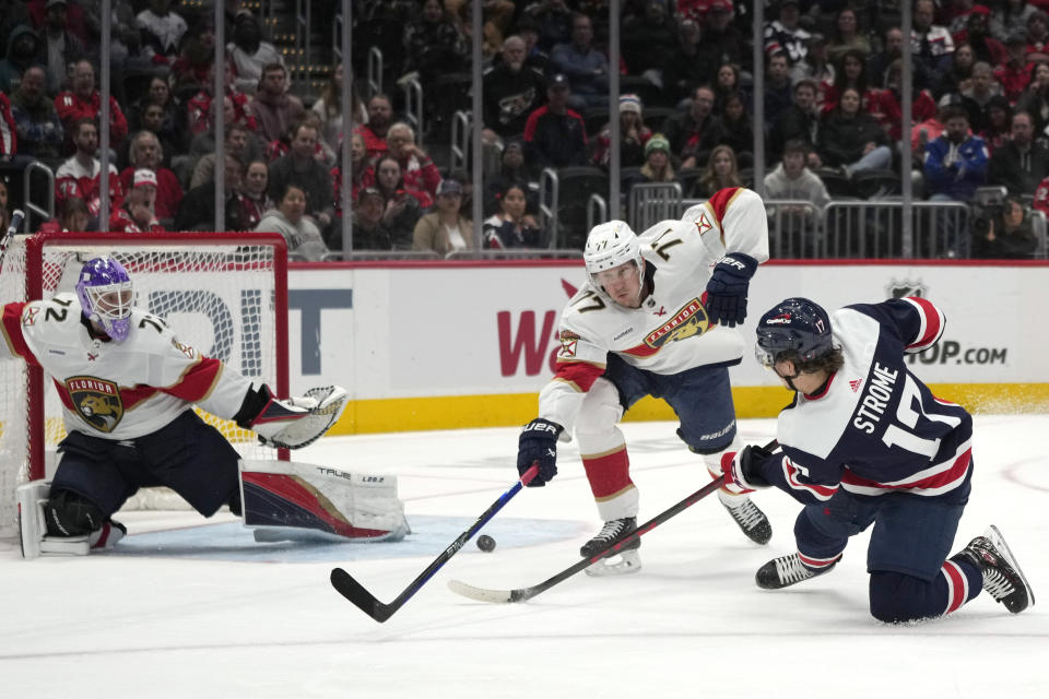 Washington Capitals center Dylan Strome (17) shoots on goal past Florida Panthers defenseman Niko Mikkola (77) as Florida Panthers goaltender Sergei Bobrovsky (72) defends during the second period of an NHL hockey game, Wednesday, Nov. 8, 2023, in Washington. (AP Photo/Mark Schiefelbein)