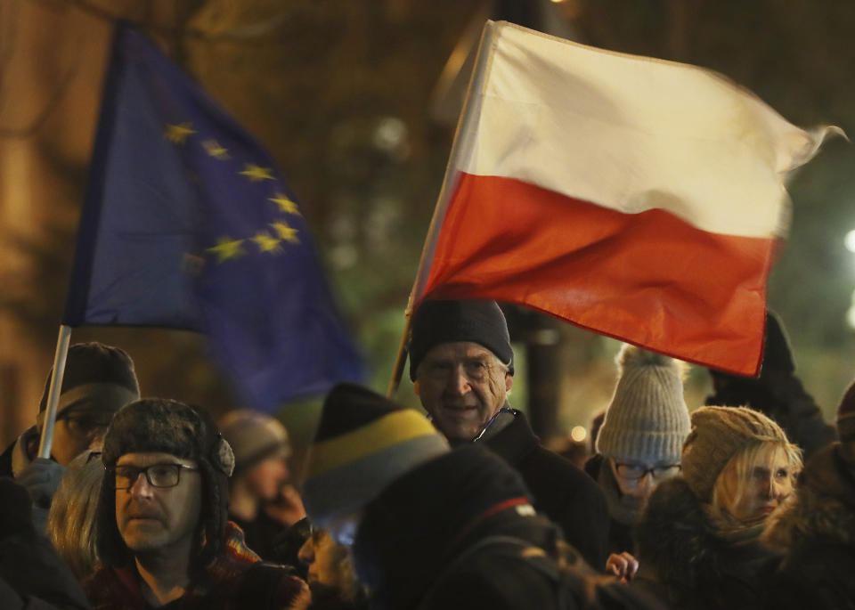 People holding a Poland and European Union flags take part in a protest outside Poland's parliament building as lawmakers voted to approve the much-criticized legislation that allows politicians to fire judges who criticize their decisions, in Warsaw, Poland, Thursday, Jan. 23, 2020. Poland's lawmakers gave their final approval Thursday to legislation that will allow politicians to fire judges who criticize their decisions, a change that European legal experts warn will undermine judicial independence. (AP Photo/Czarek Sokolowski)