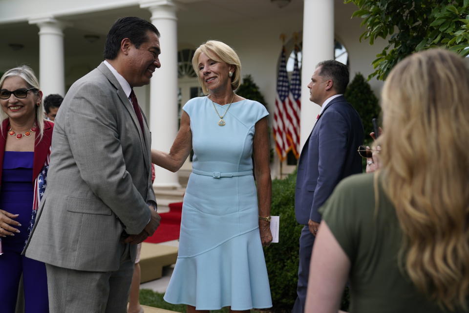 Education Secretary Betsy DeVos speaks with Jesus Marquez, President of Marquez Group Strategies, after President Donald Trump signed an executive order on the "White House Hispanic Prosperity Initiative," in the Rose Garden of the White House, Thursday, July 9, 2020, in Washington. (AP Photo/Evan Vucci)