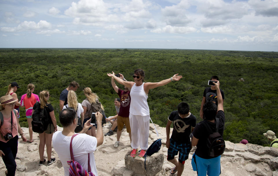 En esta fotografía del 1 de agosto de 2018 una turista levanta los brazos para una fotografía en la cima de una pirámide del sitio arqueológico maya de Cobá, en la península de Yucatán, México. El ganador de las elecciones presidenciales de México, Andrés Manuel López Obrador quiere construir un tren que iría de Cancún, en el estado de Quintana Roo, a Palenque, en Chiapas. (AP Foto/Eduardo Verdugo)