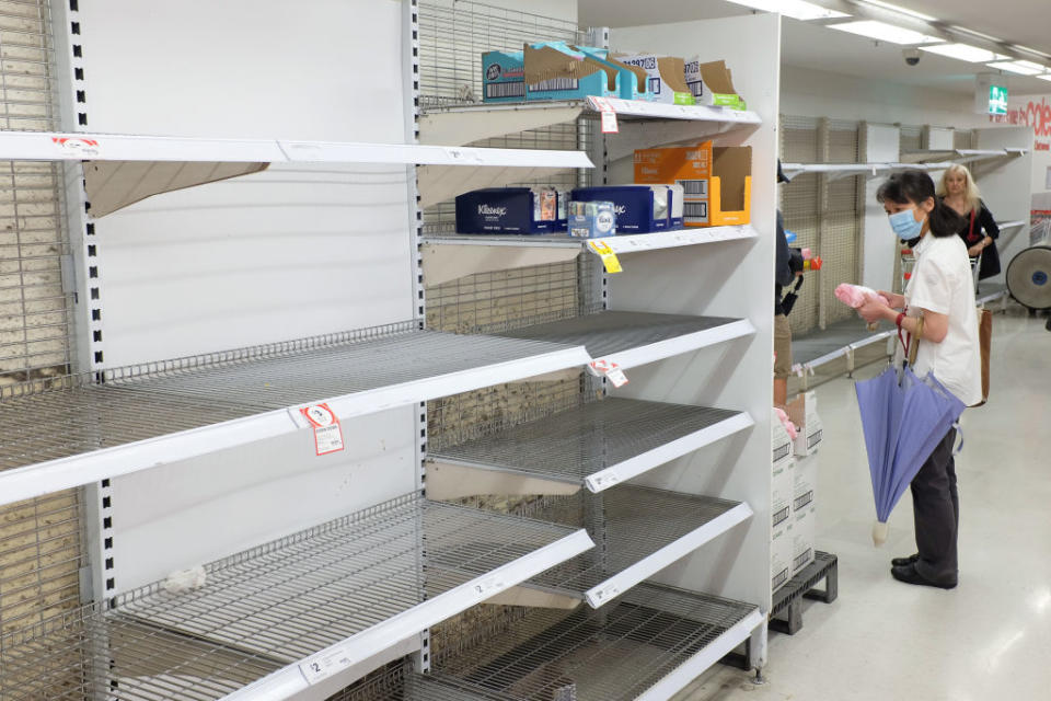Pictured is an elderly woman wearing a facemask in Coles next to an empty shelf.