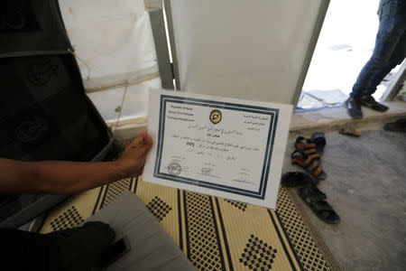 Daman Ayed, a 20-year old former rescue worker with the White Helmets holds a document at a temporary camp in Aleppo countryside, Syria July 23, 2018. Picture taken July 23, 2018. REUTERS/ Khalil Ashawi