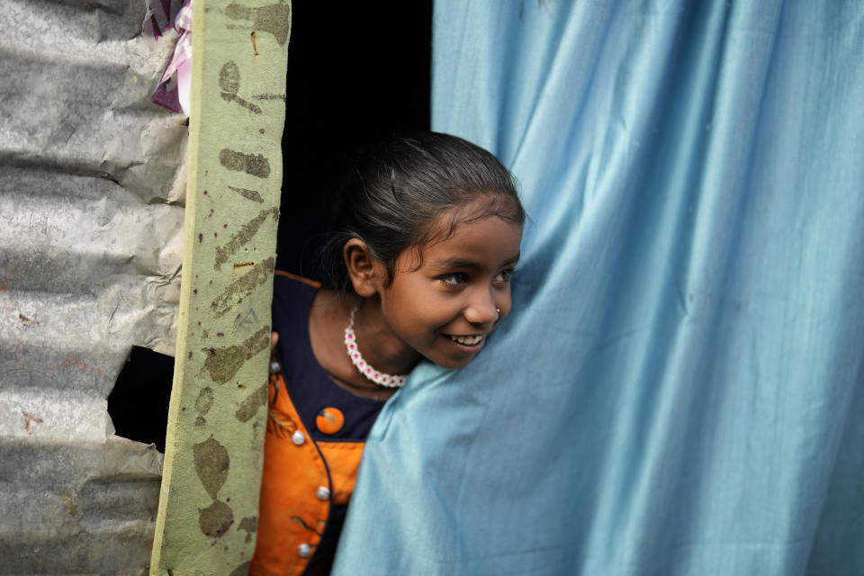 Jerifa Islam stands at the entrance of her home in a poor neighborhood in Bengaluru, India, Wednesday, July 20, 2022. In the suburban area where Jerifa and her family now live, most people are from Assam state, many forced to migrate because of climate change and dreaming of a better future. (AP Photo/Aijaz Rahi)