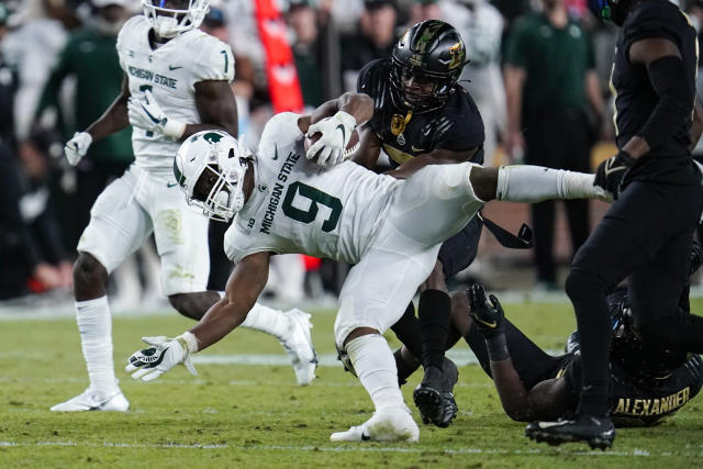 Michigan State running back Kenneth Walker III (9) is tackled by Purdue cornerback Jamari Brown (7) during the second half of an NCAA college football game in West Lafayette, Ind., Saturday, Nov. 6, 2021. (AP Photo/Michael Conroy)