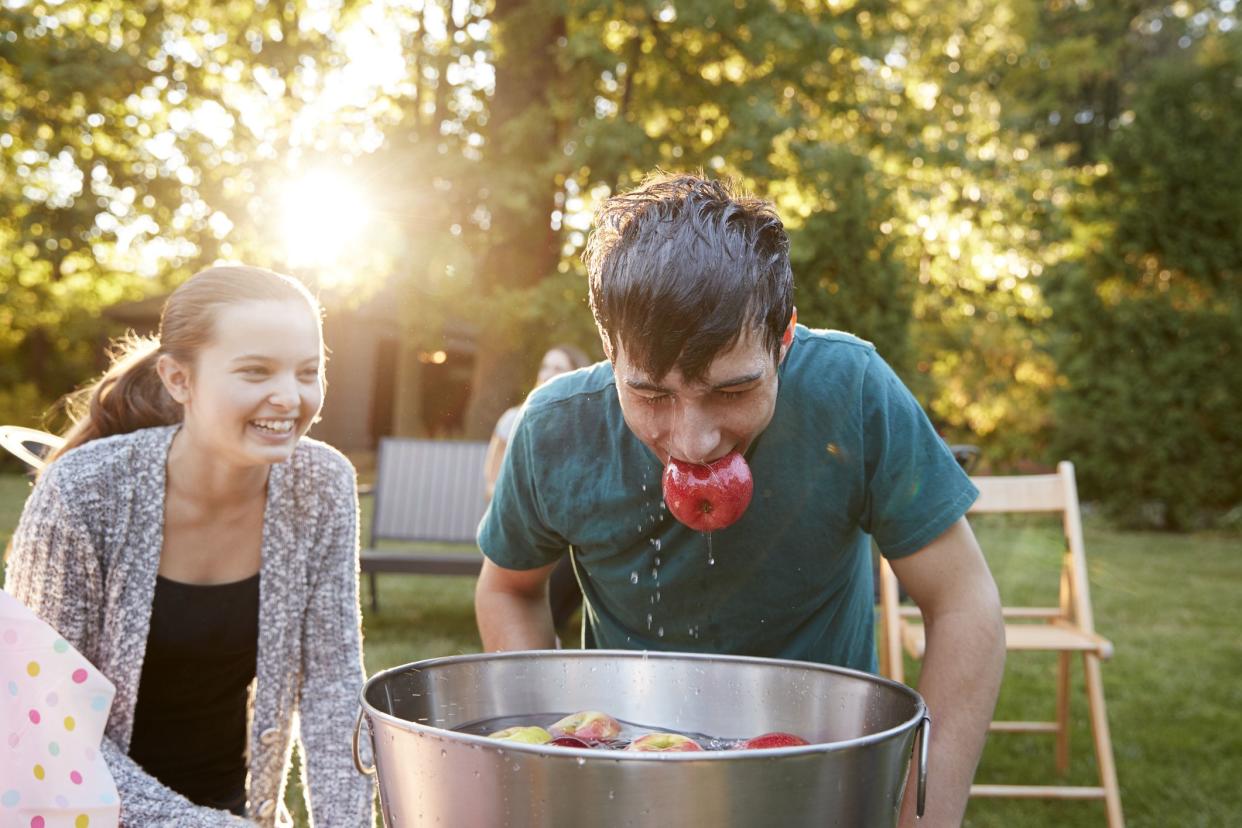 Teenage boy, apple in mouth, apple bobbing at garden party