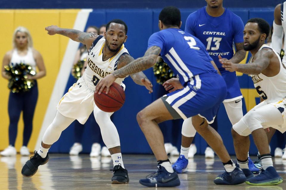 In this Thursday, Feb. 27, 2020 photo, Merrimack College guard Juvaris Hayes, left, reaches in to force a steal from Central Connecticut guard Myles Baker (2) during the second half of an NCAA college basketball game in North Andover, Mass. The Warriors have been one of the biggest surprises in college basketball, winning more games than any other first-year Division I program in history. (AP Photo/Mary Schwalm)