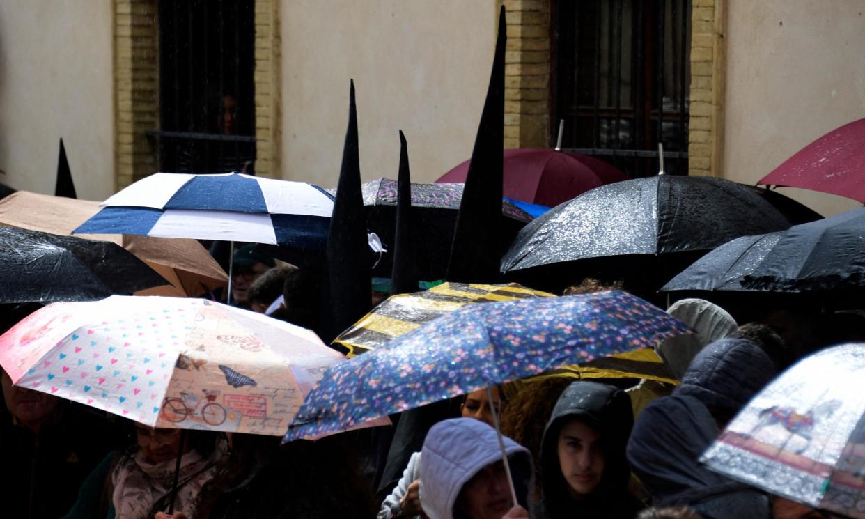 <span>People shelter from the rain under umbrellas as the San Bernardo brotherhood procession is cancelled due to rain in Seville.</span><span>Photograph: Cristina Quicler/AFP/Getty</span>