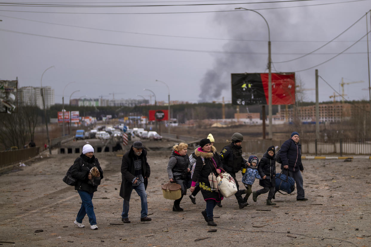 A Ukrainian police officer helps people as artillery echoes nearby while fleeing Irpin in the outskirts of Kyiv, Ukraine, Monday, March 7, 2022. (AP Photo/Emilio Morenatti)