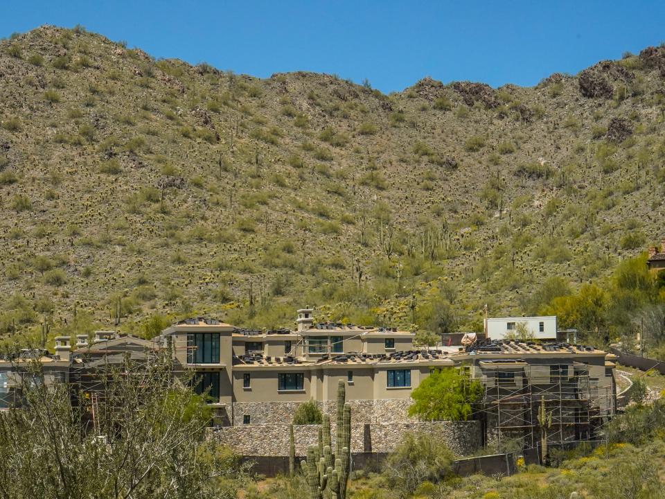 A mansion under construction against a mountain dotted with cacti