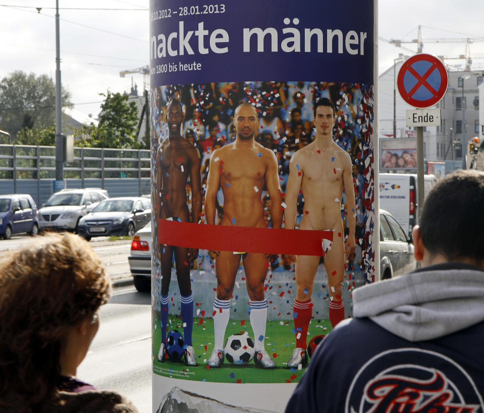 In this picture taken Oct. 18, 2012 two people walk past a poster showing three naked men which has had red tape added to cover the sensitive parts of the three men, in Vienna, Austria. Poster reads: "Naked Men". A prestigious Vienna museum, The Leopold Museum, has been forced to cover up a graphic poster advertising a new show devoted to male nudity, after protests that it is offensive. The show — "Nude Men from 1800 to Today" — opened its doors Friday Oct. 20, looking at how artists have dealt with the theme of male nudity over the centuries. (AP Photo/Ronald Zak)