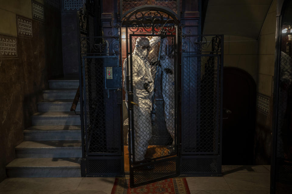 Wearing protective suits to prevent infection, mortuary workers move the body of an elderly person who died of COVID-19 from an elevator after removing it from a nursing home in Barcelona, Spain, Friday, Nov. 13, 2020. (AP Photo/Emilio Morenatti)