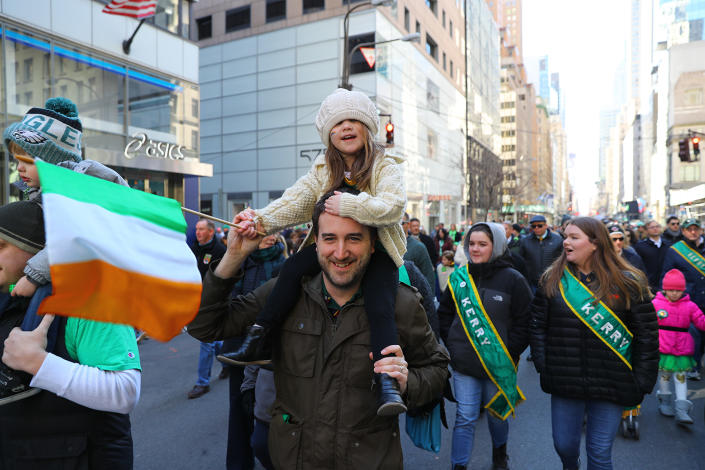 <p>A young girl waves a flag as she gets a ride while her dad marches in the St. Patrick’s Day parade on March 17, 2018, in New York. (Photo: Gordon Donovan/Yahoo News) </p>