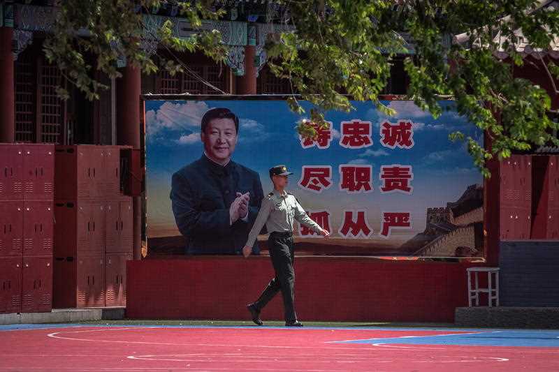 A Chinese People's Liberation Army (PLA) soldier walks past a banner depicting Chinese President Xi Jinping near the Forbidden City, in Beijing, China.