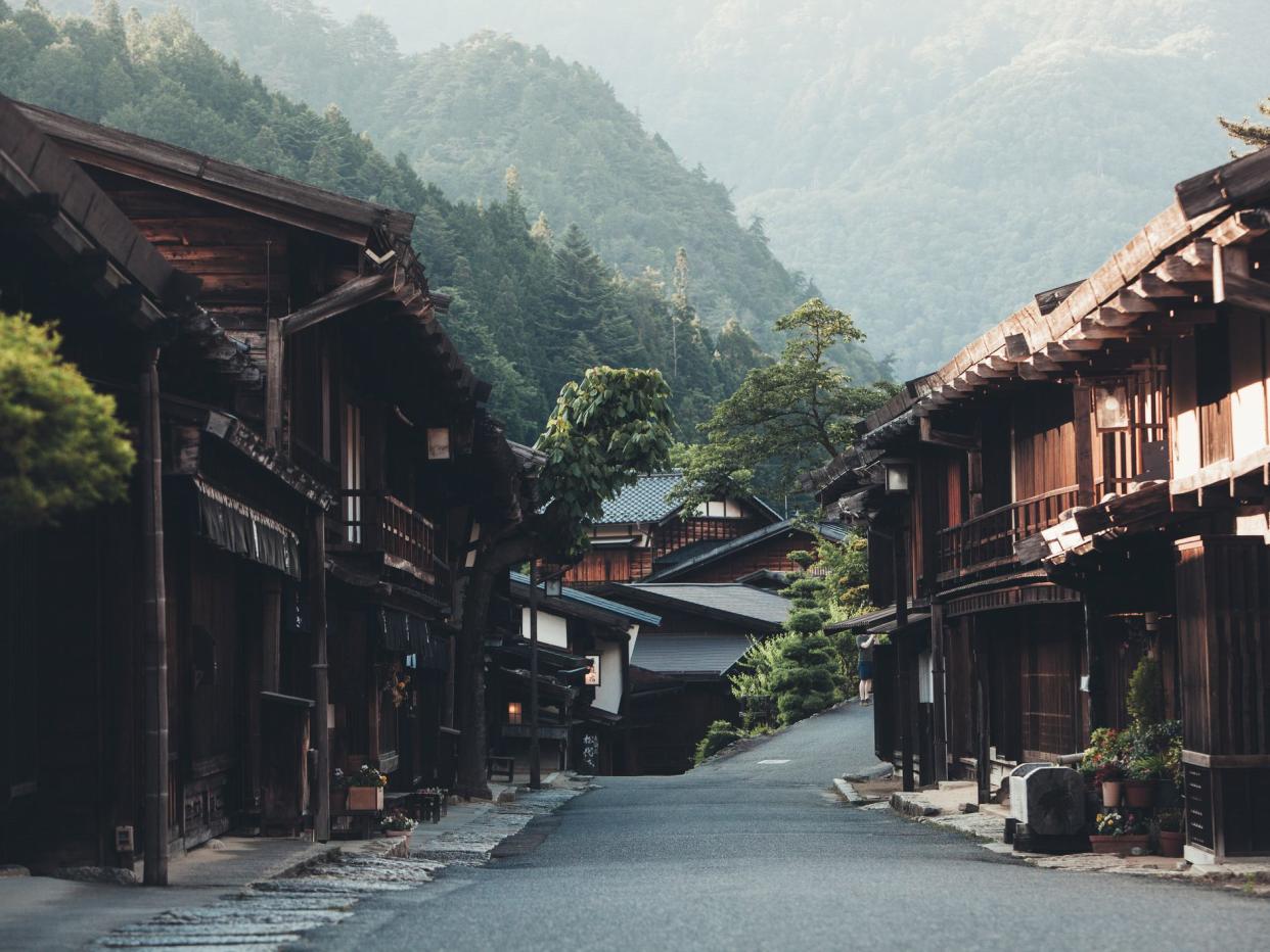 On a sunny day on the Nakasendo trail, the pathway connecting Kyoto and Tokyo in Japan a travelling man is hiking with a backpack and embracing both the nature and culture of this beautiful Edo period rural environment.